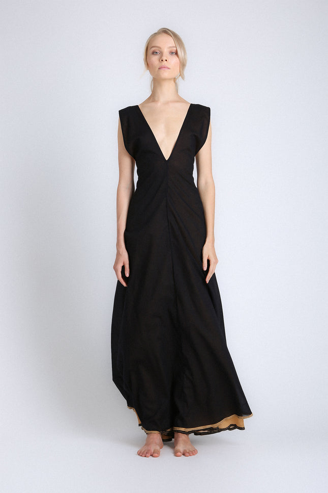 Model wearing the Eva Dress with a voluminous, flowing silhouette, contrasting double layers, self-tie V-neckline, and low open back.