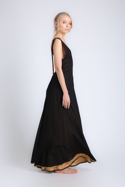 Model wearing the Eva Dress with a voluminous, flowing silhouette, contrasting double layers, self-tie V-neckline, and low open back.