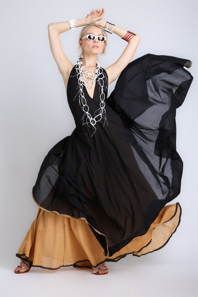 Model wearing the Eva Dress with a voluminous, flowing silhouette, contrasting double layers, self-tie V-neckline, and low open back.