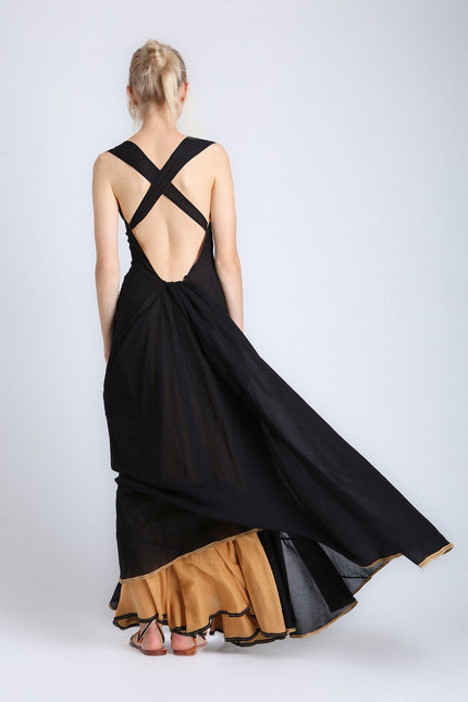 Model wearing the Eva Dress with a voluminous, flowing silhouette, contrasting double layers, self-tie V-neckline, and low open back.