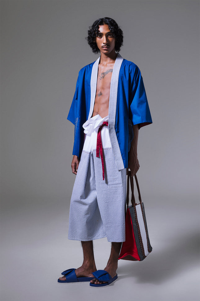 Model wearing Manda Thai Pants in pure cotton with relaxed unisex fit, vertical stripes, and red waist belt.