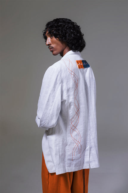 Model wearing Mackenzie Jacket in pure linen, featuring a slim structured silhouette, indigo and tangerine pockets, and hand-stitched detailing.