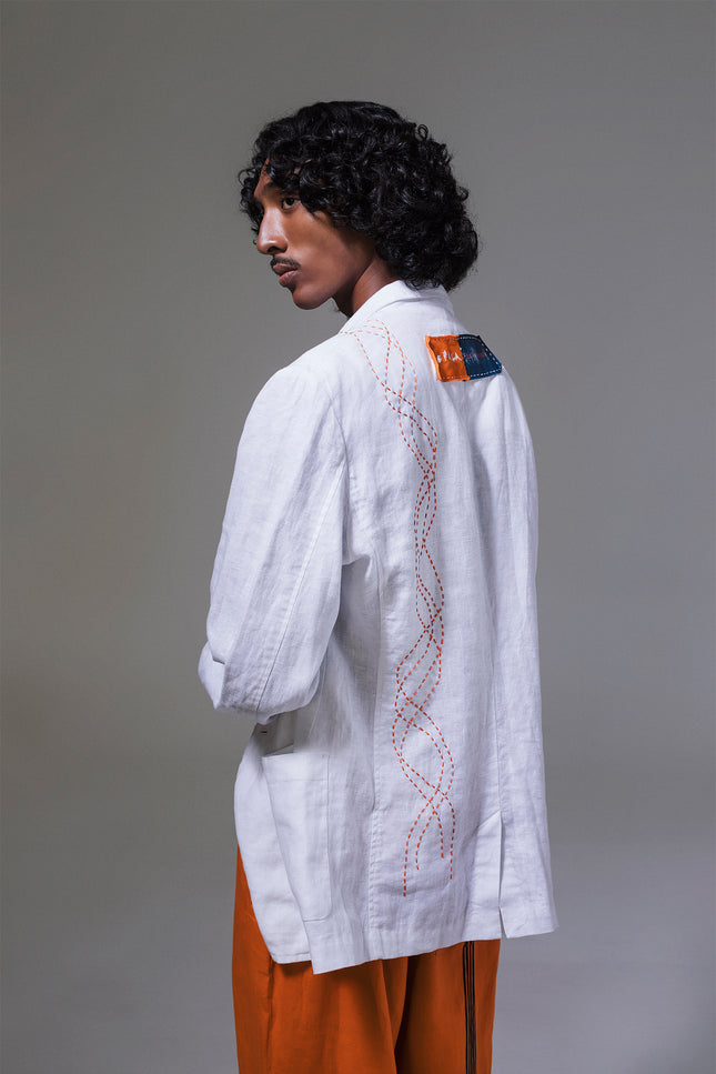Model wearing Mackenzie Jacket in pure linen, featuring a slim structured silhouette, indigo and tangerine pockets, and hand-stitched detailing.