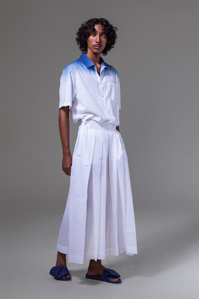 Model wearing cotton camp shirt with natural indigo dip-dye at the top, featuring short sleeves, side slits, and open collar.