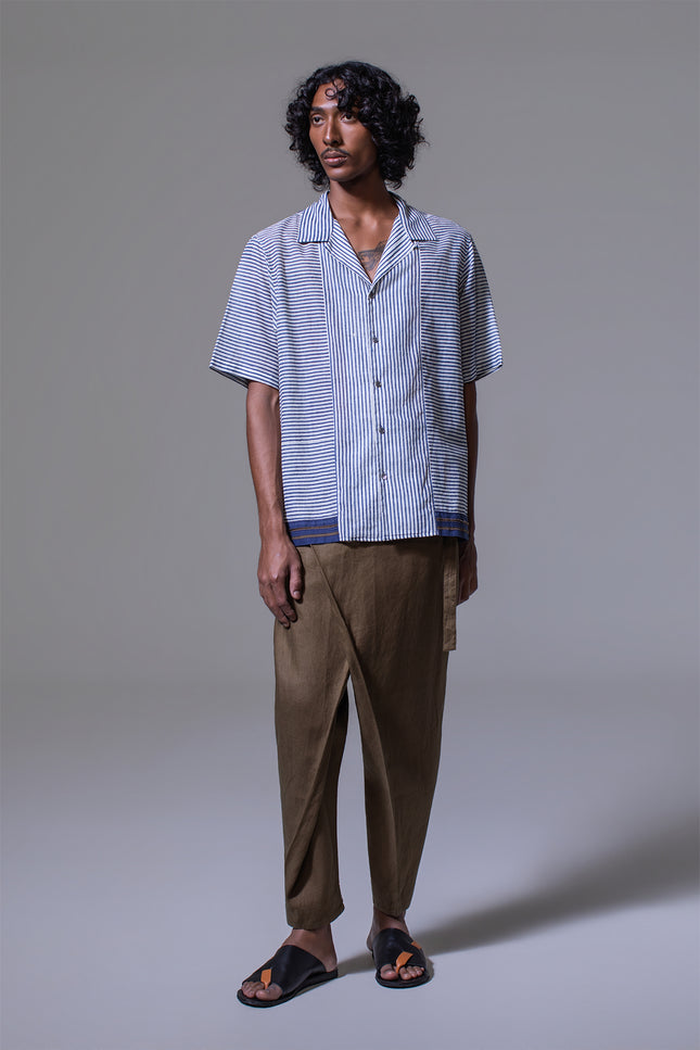 Model wearing Mosses Camp Shirt in pure cotton with vertical and horizontal stripe prints, open notch collar, clean button-up front, border applique at the hem, short sleeves, and side slits for a relaxed and characterful resort look.