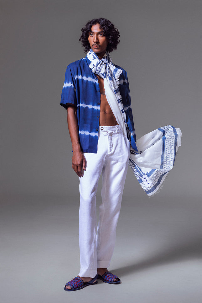 Model wearing Leon Camp Shirt in pure cotton with tie-dye stripe pattern, open notch collar, button-and-loop closure, clean button-up front, short sleeves, and side slits for a relaxed and serene warm-weather look.