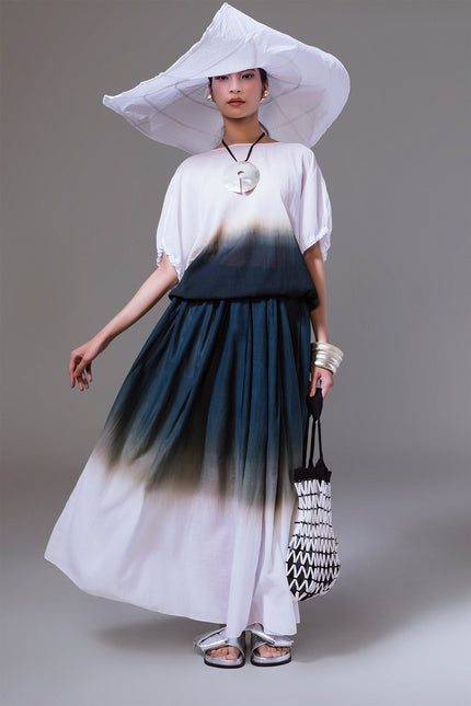 Model wearing the Matrena Top in lightweight cotton, featuring a relaxed silhouette with boat neckline, softly gathered sleeves, indigo dip-dye effect, and adjustable drawstring hem for versatile styling.