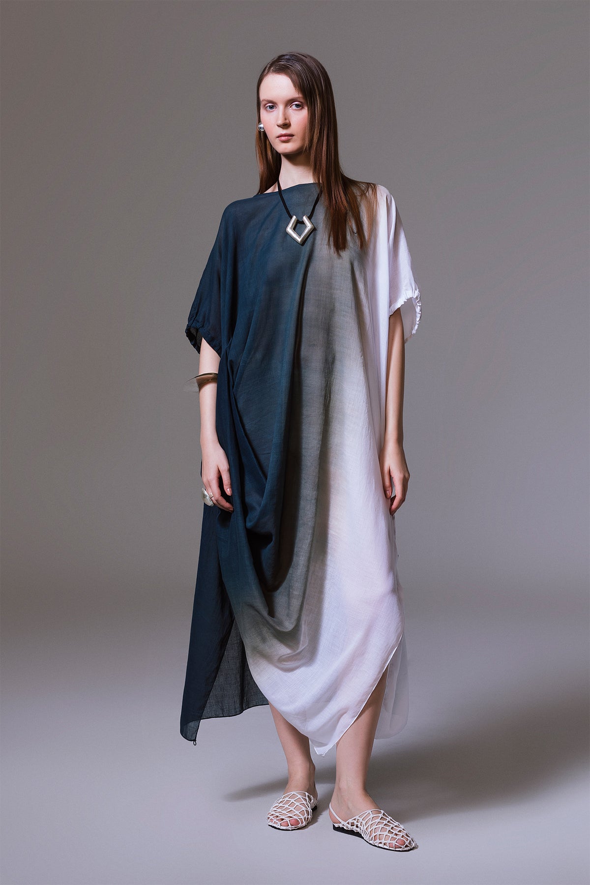 Model wearing black, grey, and white ombré cotton dress with front drape and relaxed silhouette.