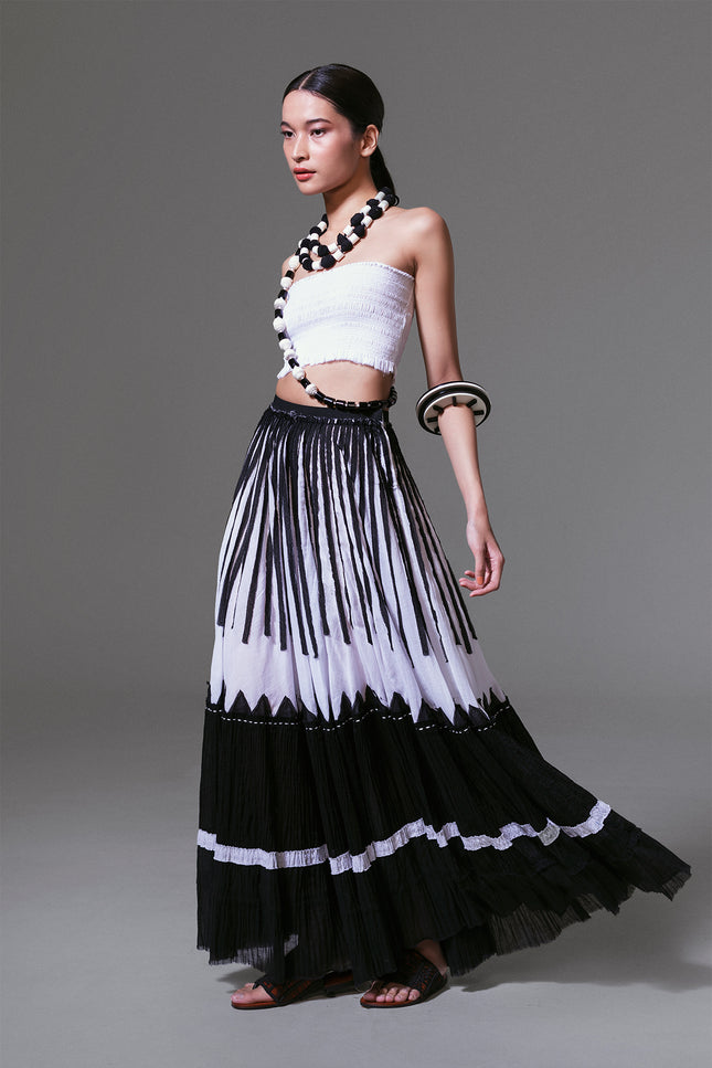 Model wearing black and white crinkled cotton maxi skirt with bold vertical appliqué, styled in flowing movement.