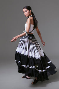 Model wearing black and white crinkled cotton maxi skirt with bold vertical appliqué, styled in flowing movement.