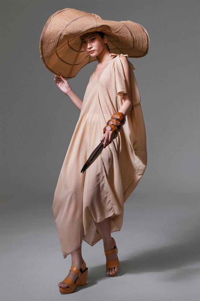 Model wearing long sabbia kaftan with V neckline, slit sleeves, and tie detail at the shoulder in lightweight cotton mousseline.