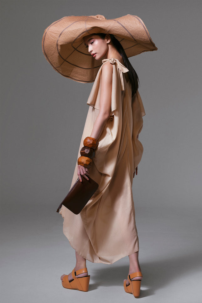 Model wearing long sabbia kaftan with V neckline, slit sleeves, and tie detail at the shoulder in lightweight cotton mousseline.