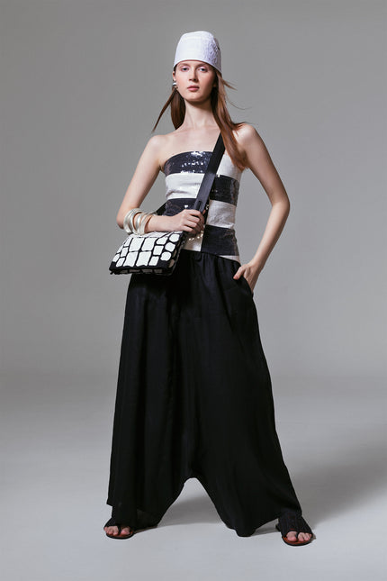 Model wearing Madeon Pants in lightweight linen with low-crotch silhouette, drawstring waist, and draped skirt-like effect.