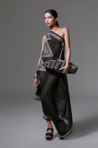 Model wearing black one-shoulder asymmetrical dress with white geometric ribbon appliqué and sheer silk-cotton finish.