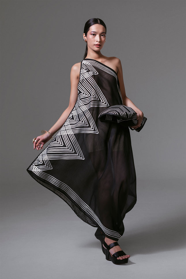 Model wearing black one-shoulder asymmetrical dress with white geometric ribbon appliqué and sheer silk-cotton finish.