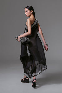 Model wearing black one-shoulder asymmetrical dress with white geometric ribbon appliqué and sheer silk-cotton finish.