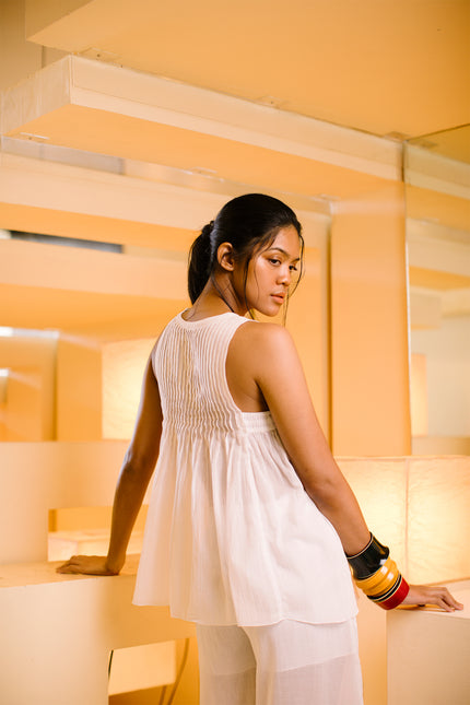 Model wearing BIASA Evana Top in lightweight cotton, featuring a sleeveless design, vertical micro-pleats, and a wide A-line silhouette.