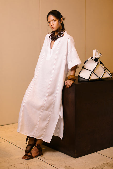 Model wearing Lenore Kaftan in linen, featuring relaxed kimono sleeves, deep V-neckline, high side slits, and delicate fagoting details.