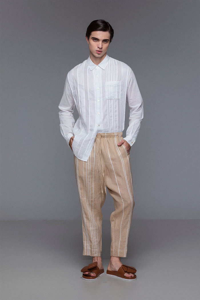 Model wearing white collared shirt with wrist cuffs, button placket, and tonal linen-cotton patchwork details.