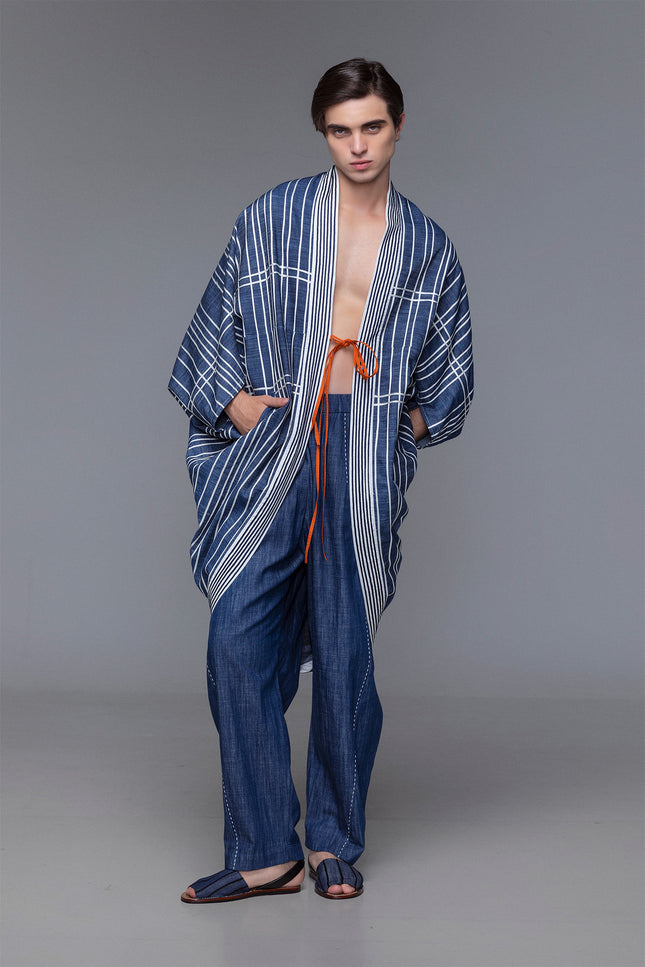 Model wearing Marlie Outer in cotton with diamond-shaped silhouette, satin ribbon applique, and ribbon fastening.