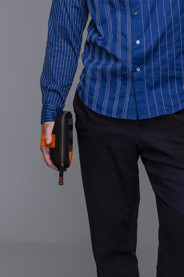 Canvas pouch with bold tarpaulin stripe appliqué, zipper closure, contrast handle, and internal mesh pocket.