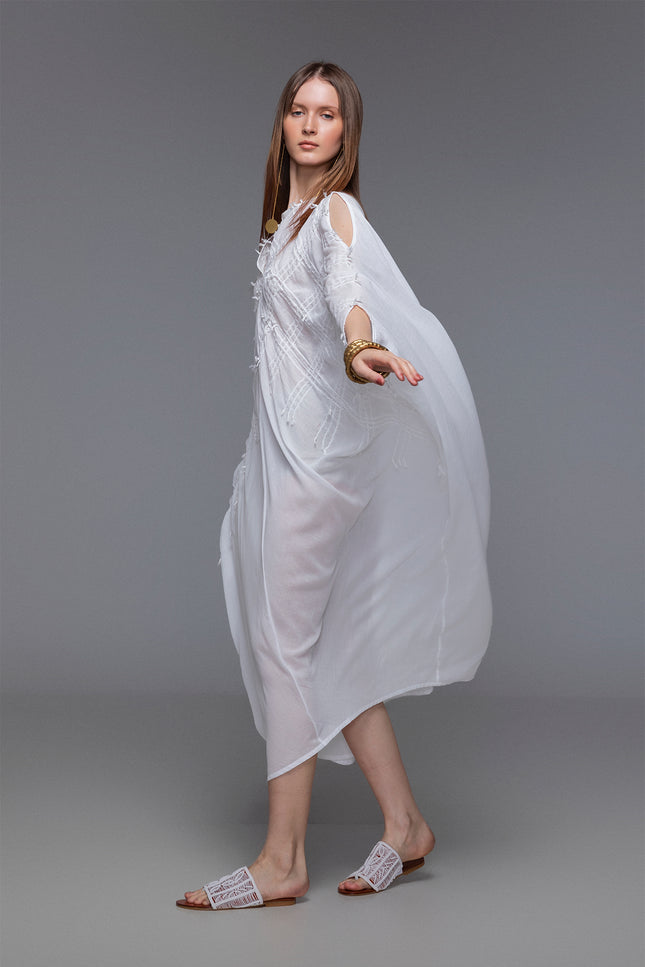 Model wearing white Magnolia Kaftan in sheer cotton with batwing silhouette, slit shoulders, and hand-stitched details.