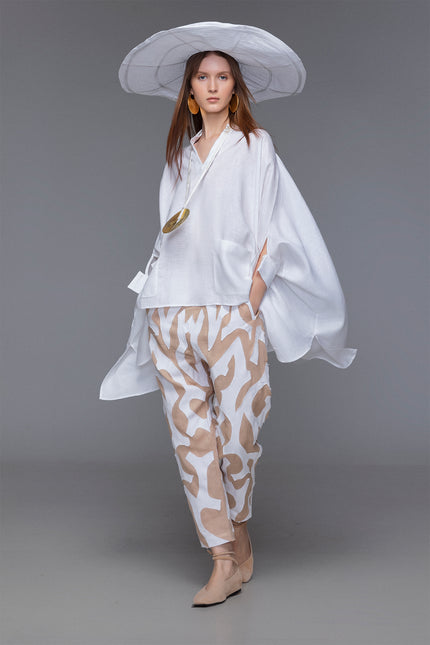 Model wearing Mason Pants with loose tapered silhouette, wide low crotch, contrasting tiger-like hand-cut appliqué, elastic waistband with inner drawstrings, and functional pokets for a relaxed yet refined resort look.
