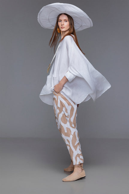 Model wearing Mason Pants with loose tapered silhouette, wide low crotch, contrasting tiger-like hand-cut appliqué, elastic waistband with inner drawstrings, and functional pokets for a relaxed yet refined resort look.