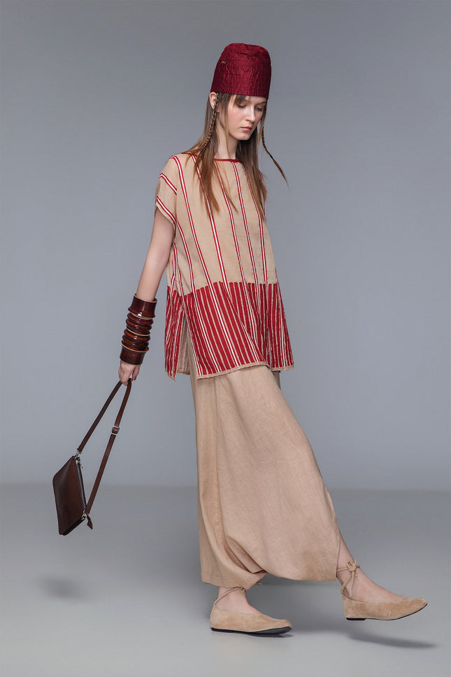 Asymmetrical draped skirt-pants in bordeaux, wide leg with fluid draping, shown on model.