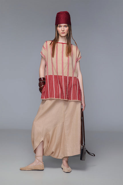 Asymmetrical draped skirt-pants in bordeaux, wide leg with fluid draping, shown on model.