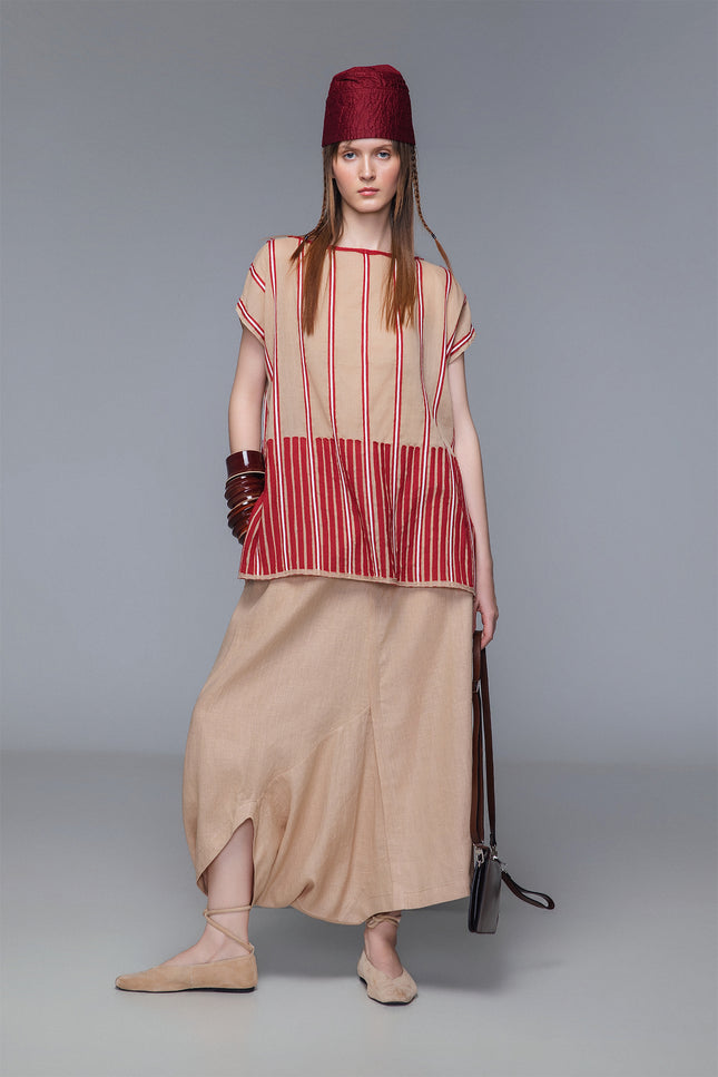 Asymmetrical draped skirt-pants in bordeaux, wide leg with fluid draping, shown on model.