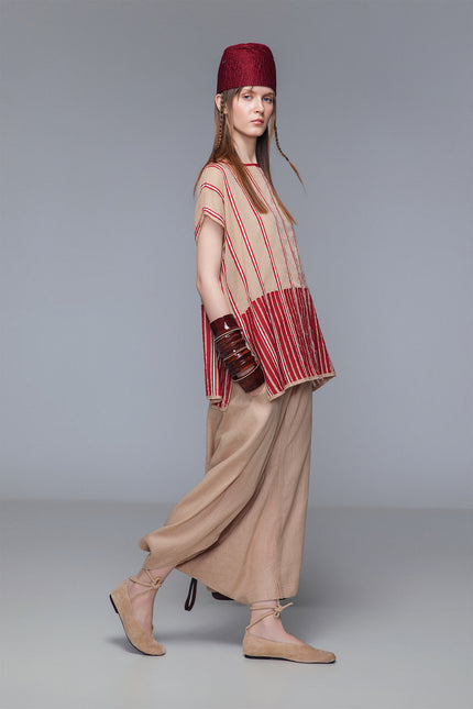 Asymmetrical draped skirt-pants in bordeaux, wide leg with fluid draping, shown on model.