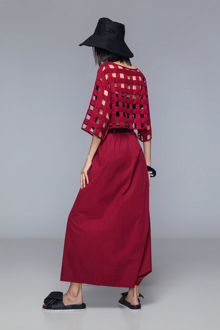 Asymmetrical draped skirt-pants in bordeaux, wide leg with fluid draping, shown on model.