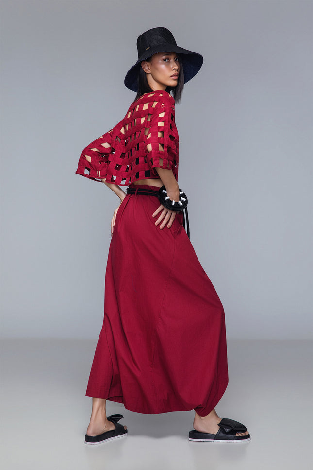 Asymmetrical draped skirt-pants in bordeaux, wide leg with fluid draping, shown on model.
