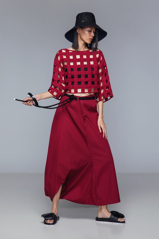 Asymmetrical draped skirt-pants in bordeaux, wide leg with fluid draping, shown on model.