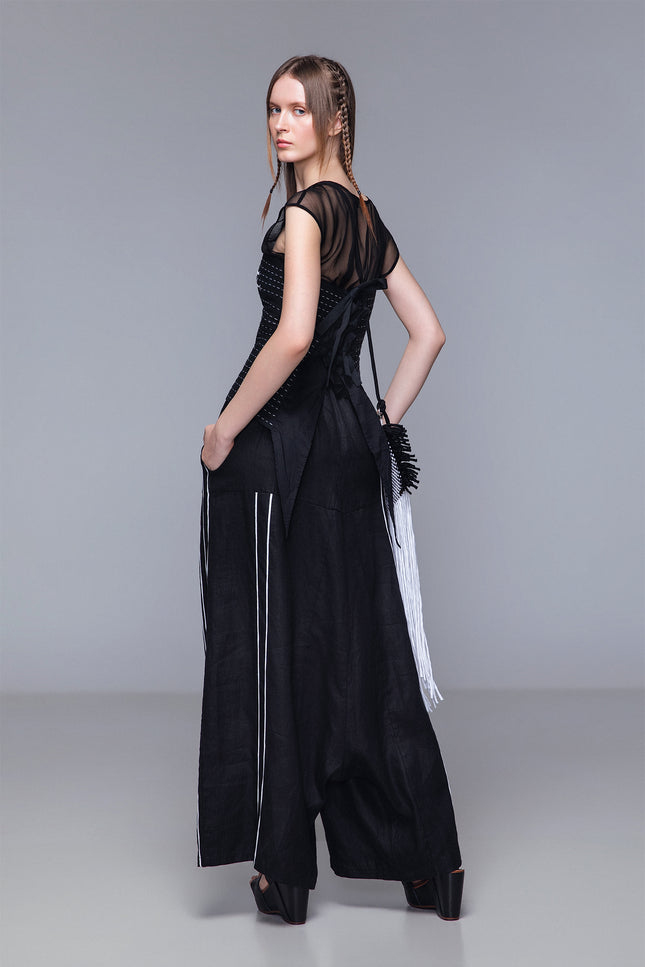 Model wearing Matana Corset in pure cotton with adjustable back tail and strap closure, featuring monochrome ribbon detailing and contrast hand stitching for a refined statement look.