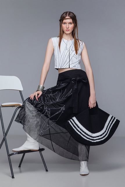 Model wearing Maldia Skirt in pure cotton with double-fabric construction, sheer hem, and tropical flower embroidery for fluid, textured styling.