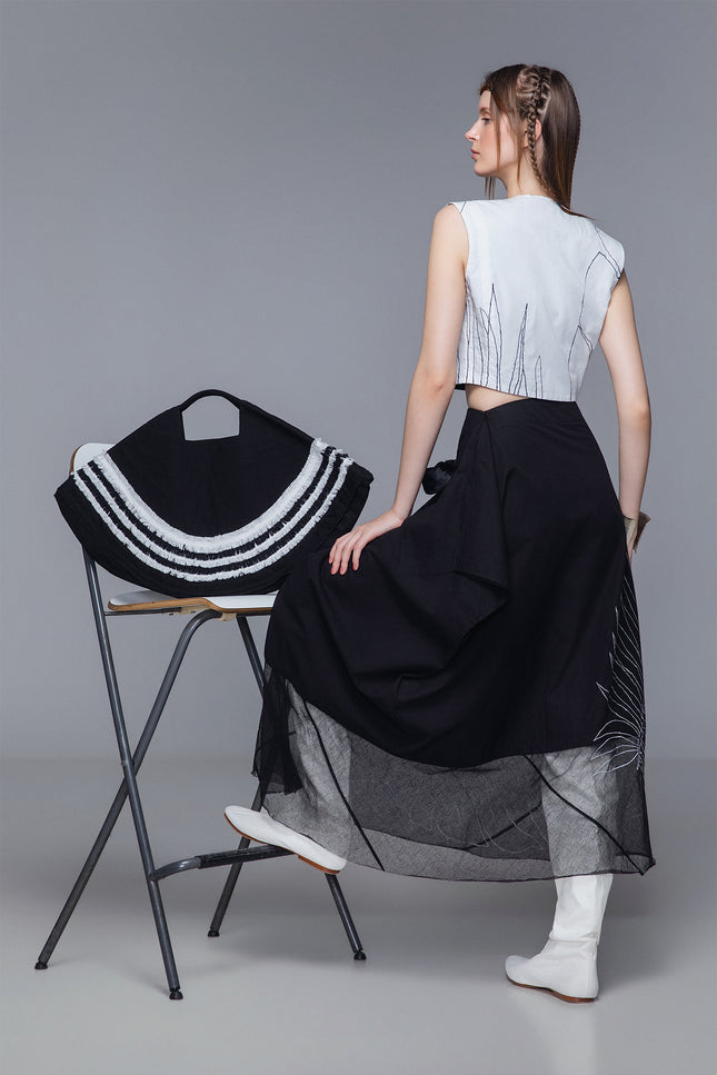 Model wearing Maldia Skirt in pure cotton with double-fabric construction, sheer hem, and tropical flower embroidery for fluid, textured styling.