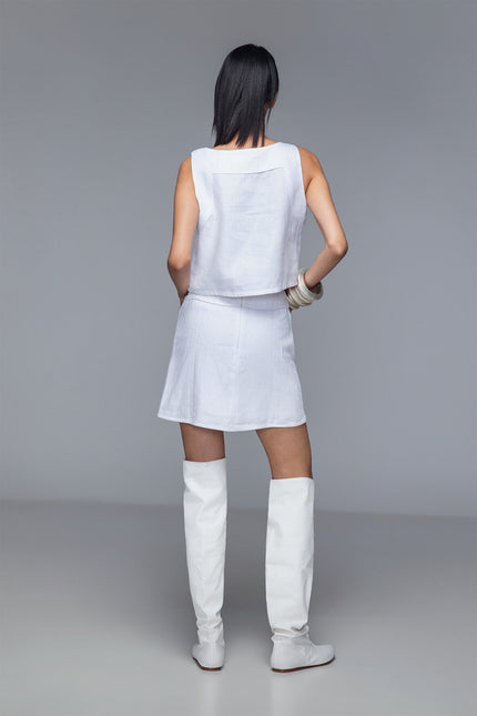 Model wearing Minie Skirt in pure linen with straight-cut silhouette, front grid-like square appliqué, and solid back design for a bold, architectural look.