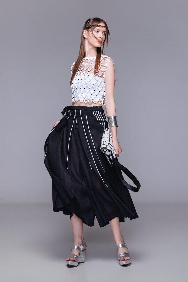 Model wearing Netta Cropped Top handcrafted with macrame, featuring a diamond net structure, sleeveless one-size silhouette, and open-knit design for textured layering.