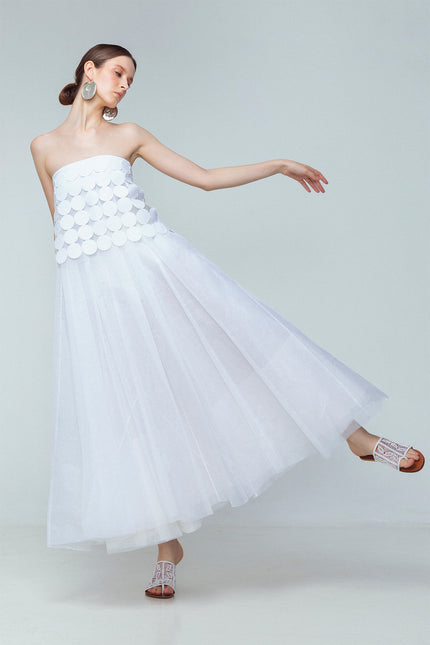 Model wearing white linen tube top made from coin-shaped appliques with ribbon tie closures.