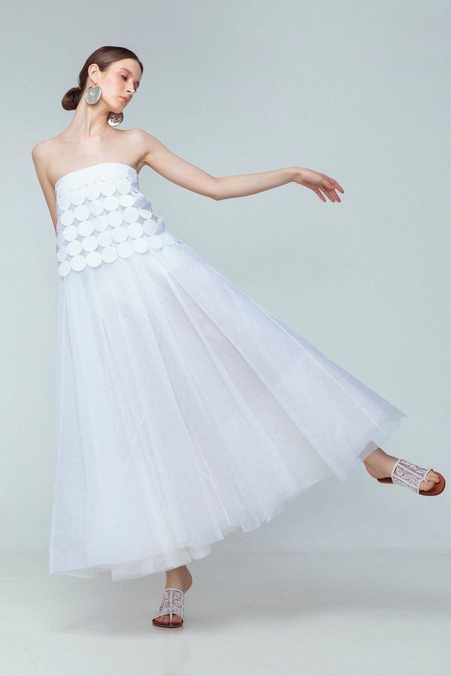 Model wearing white linen tube top made from coin-shaped appliques with ribbon tie closures.