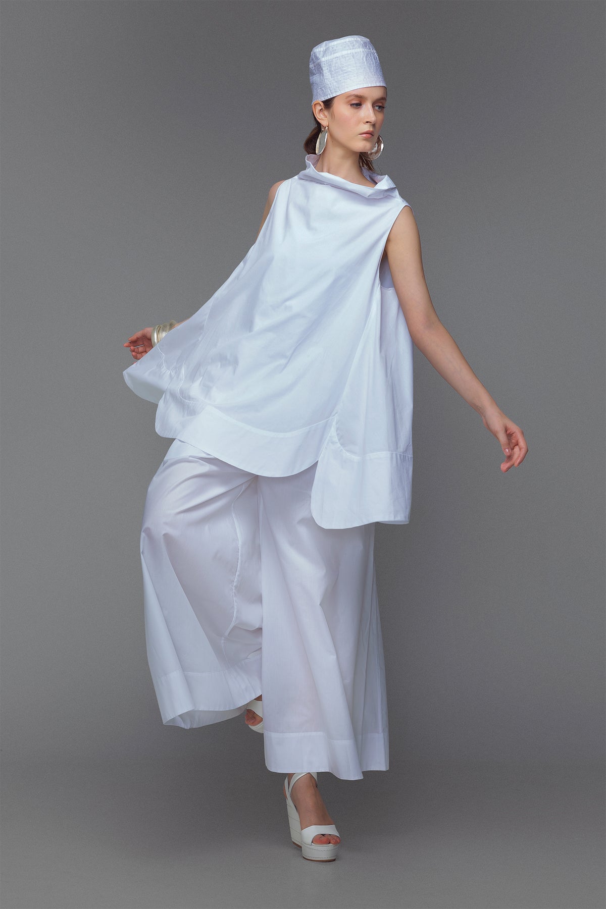 Model wearing cotton mini dress with cowl neck in sleek white.