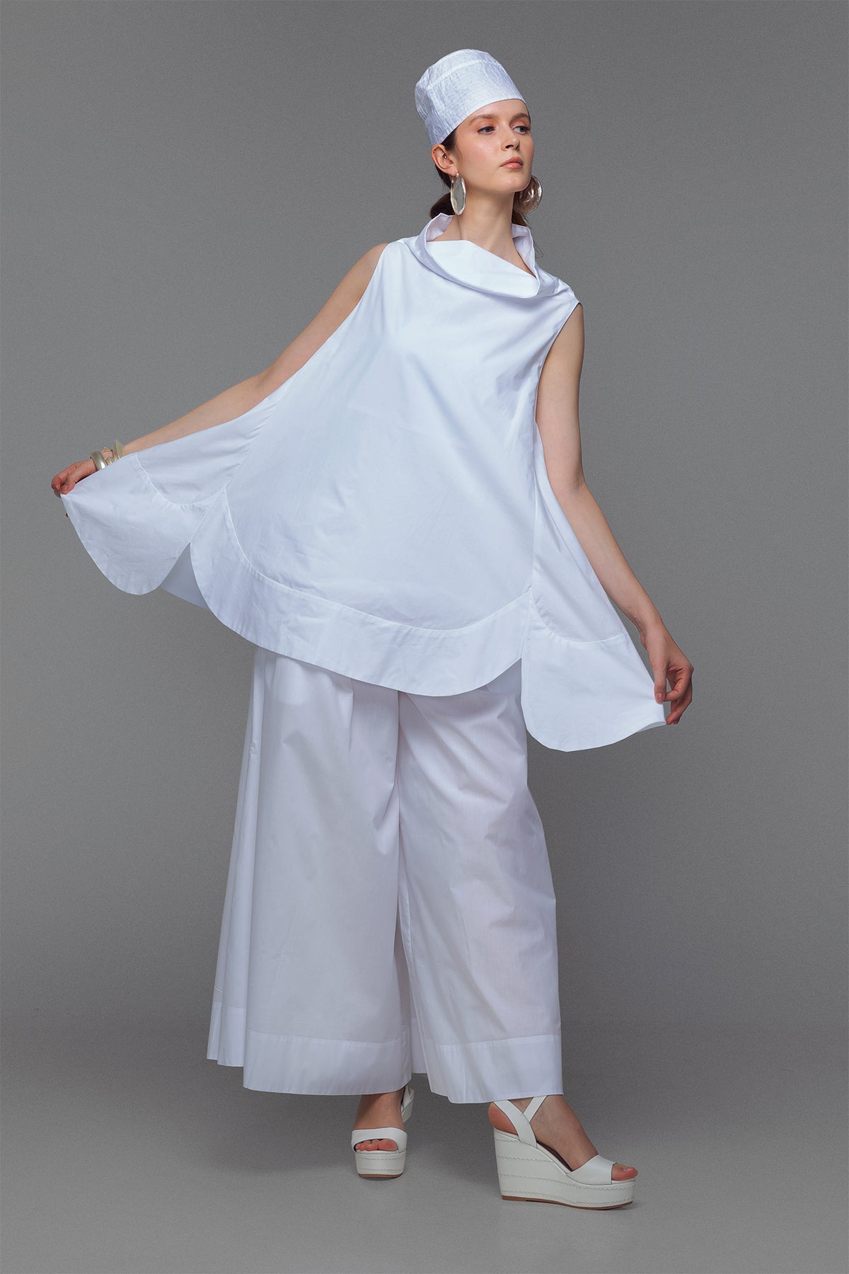 Model wearing cotton mini dress with cowl neck in sleek white.