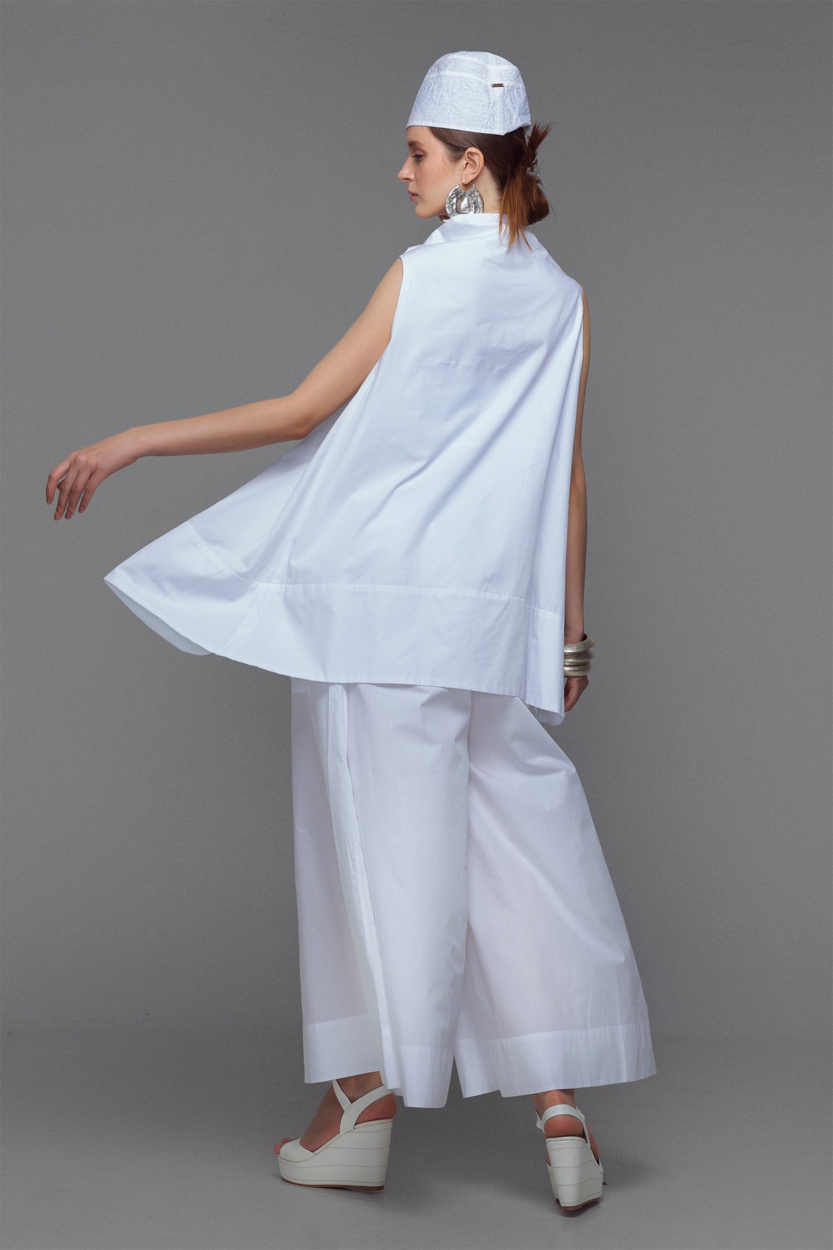Model wearing cotton mini dress with cowl neck in sleek white.
