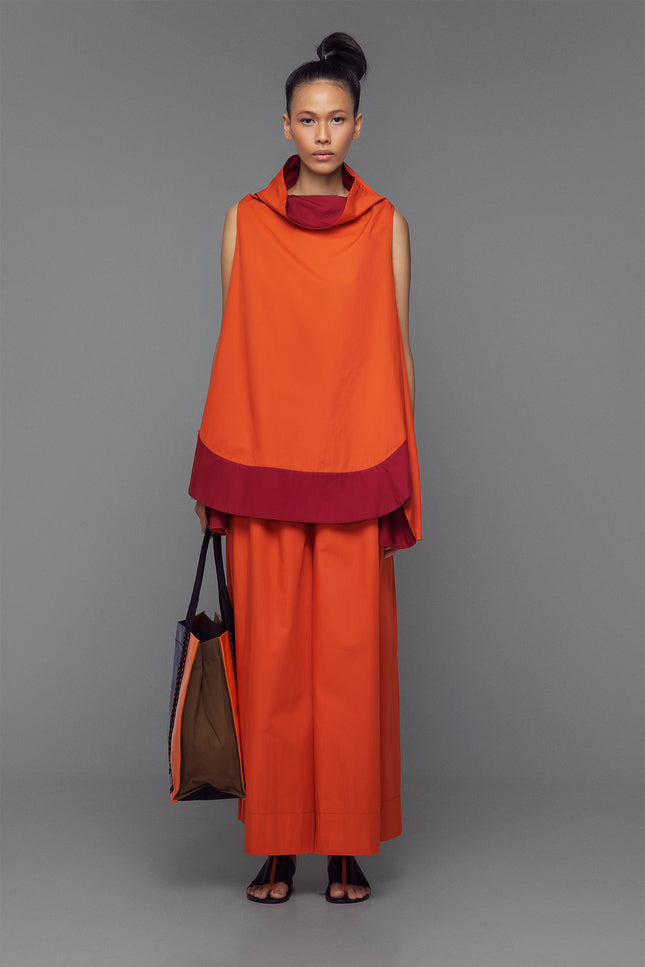 Model wearing cotton mini dress with cowl neck, shown in a color block option of tango orange and bordeaux.