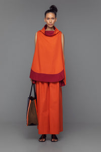 Model wearing cotton mini dress with cowl neck, shown in a color block option of tango orange and bordeaux.