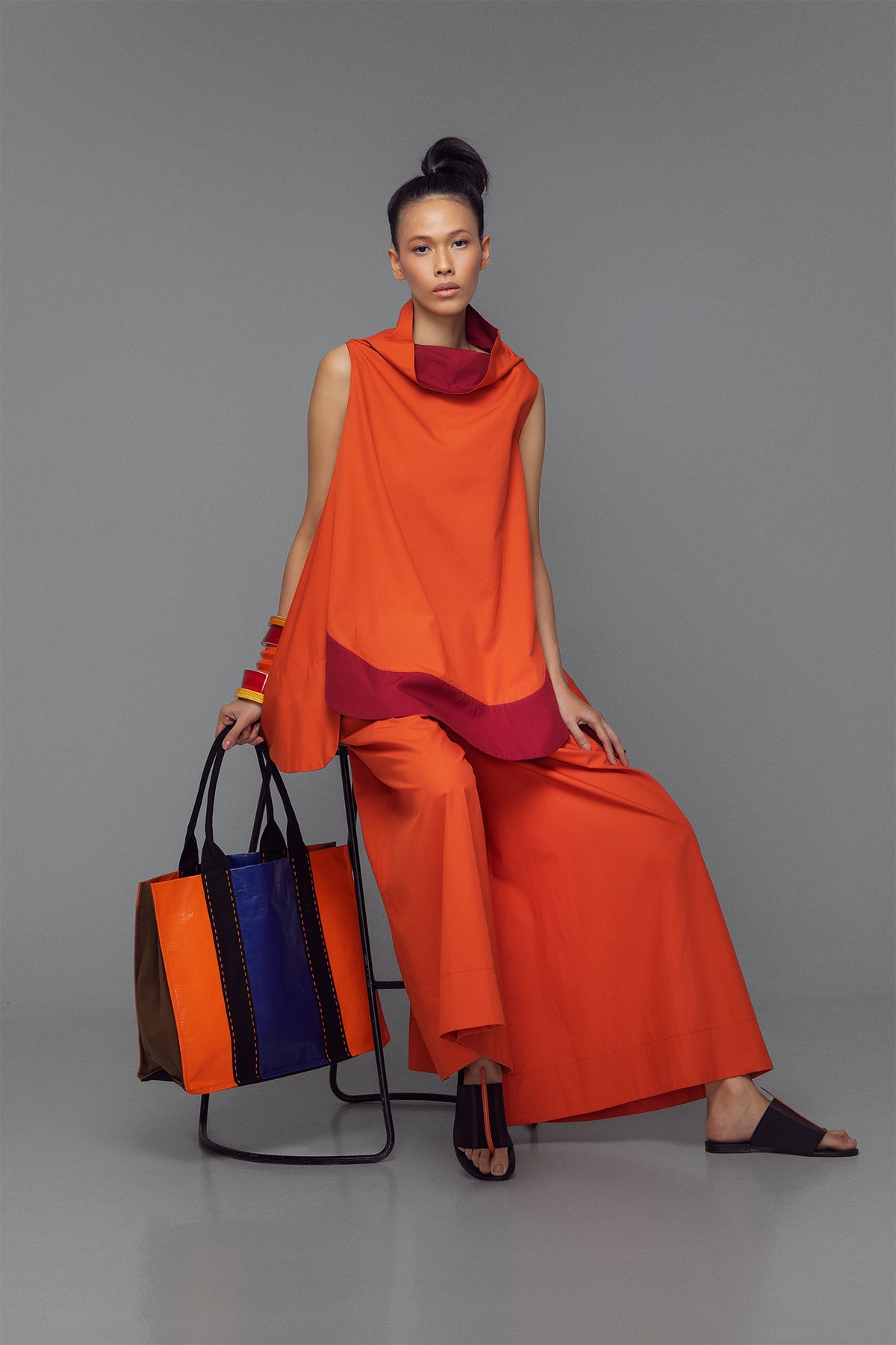 Model wearing cotton mini dress with cowl neck, shown in a color block option of tango orange and bordeaux.