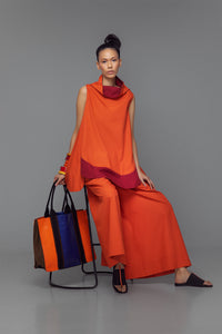 Model wearing cotton mini dress with cowl neck, shown in a color block option of tango orange and bordeaux.