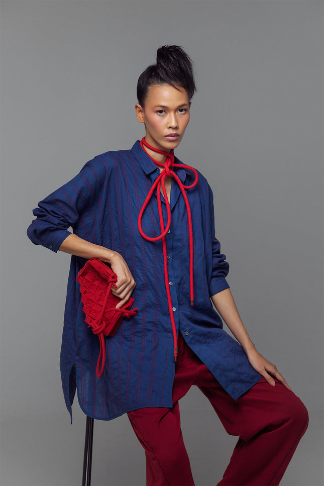 Model wearing oversized long-sleeve shirt dress with full vertical buttons, styled as a casual yet polished tunic.